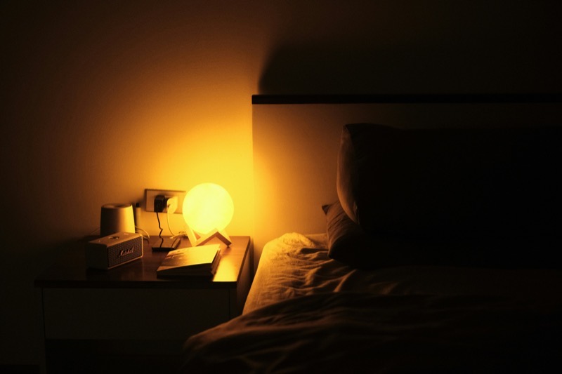 A softly lit bedroom at night with a bedside lamp on